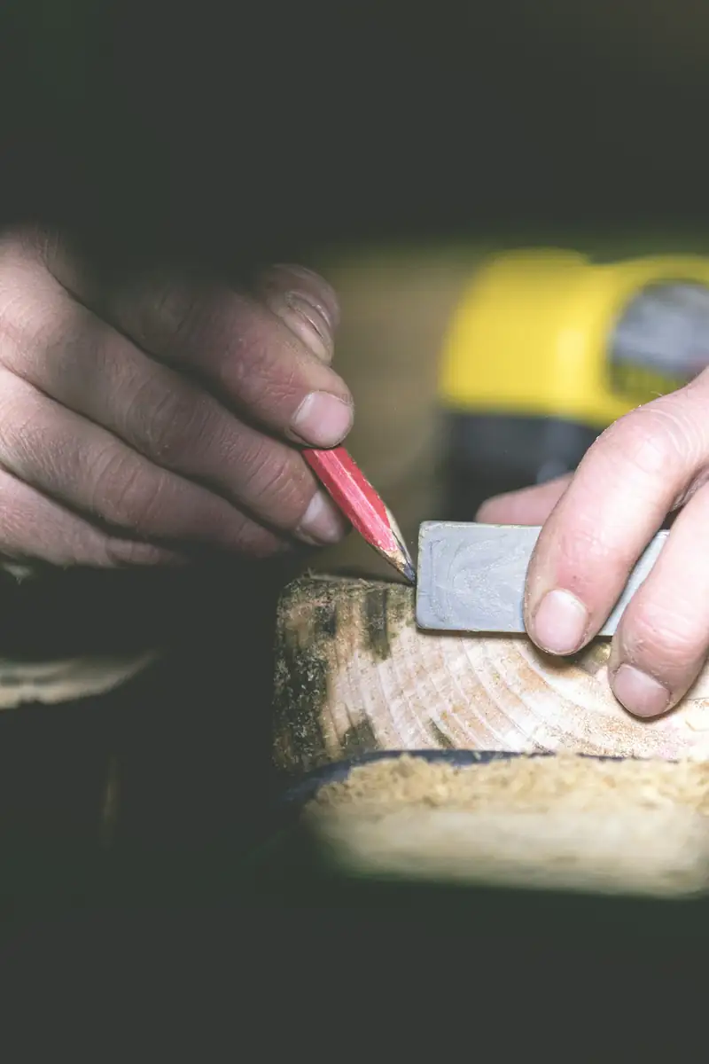 Mains qui tracent un repère au crayon avant une coupe